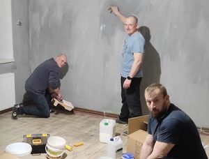 Trzech mężczyzn szykuje się do malowania ścian w pokoju.