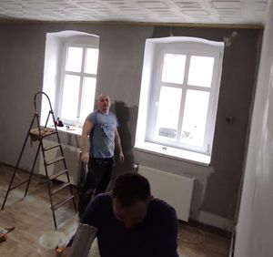Dwóch mężczyzn maluje ściany w pokoju.