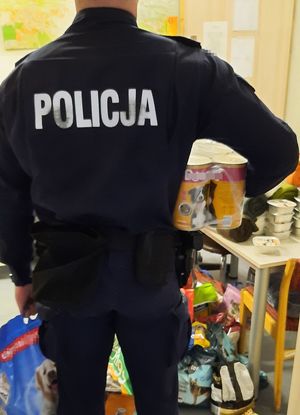 Policjant w mundurze wnosi do pokoju puszki z karmą dla zwierząt.