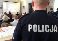 Plecy umundurowanego policjanta patrzącego na przedstawienie prezentacji multimedialnej.