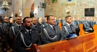 Umundurowani policjanci w mundurach galowych siedzą w ławach kościelnych.