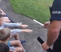 Umundurowany policjant rozdaje dzieciom odblaski.