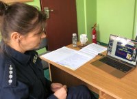 Policjantka w mundurze siedzi przy komputerze i ogląda prezentację multimedialną.