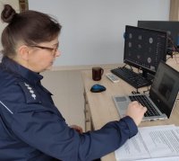 Policjantka w mundurze siedzi przy biurku i pisze na klawiaturze komputera.