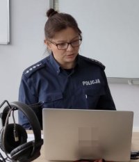 Policjantka w mundurze siedzi przed laptopem.
