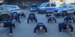 Policjanci w mundurach robią pompki na placu apelowym.