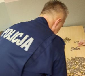 Policjant w mundurze liczy pieniądze porozrzucane na stole.