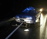 Uszkodzony samochód osobowy w nocy stoi na środku drogi.