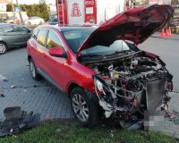 Rozbity czerwony samochód z podniesioną maską.