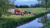 Mężczyźni stoją przy wozie strażackim a obok laweta wciąga auto osobowe na lawetę.