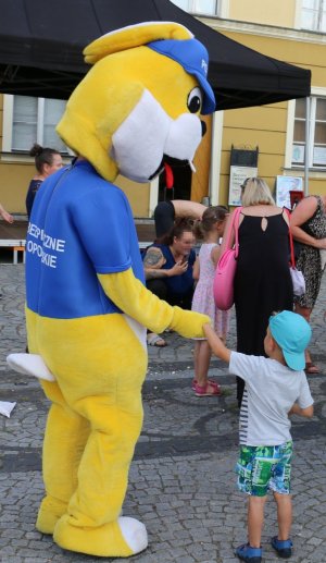 Pluszowa maskotka policyjna podje rękę dziecku.