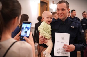 Zdjęcie przedstawia policjanta z dzieckiem na rękach.