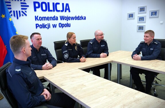 zdjęcie kolorowe: policjanci siedzą przy stole
